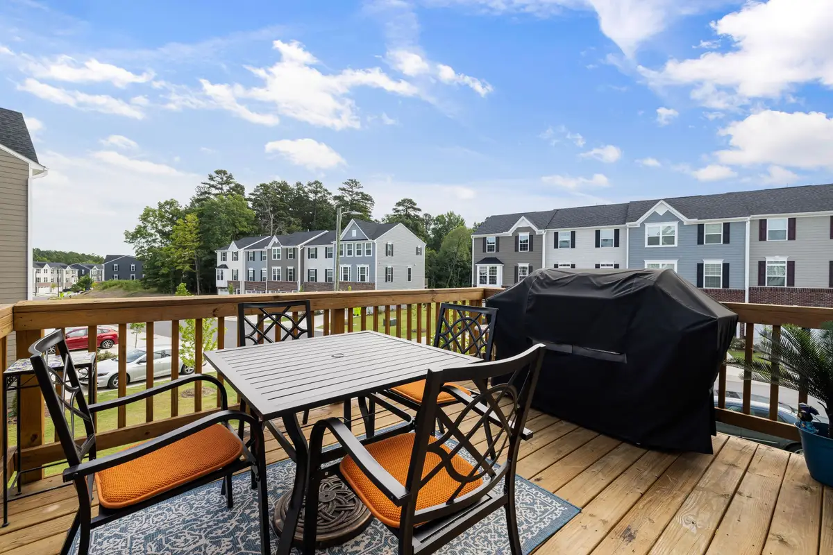 Wood backyard deck with patio table, chairs and a grill overlooking a neighborhood